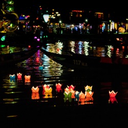 Traditional multicolored paper lanterns with candles floating down the river at night in UNESCO World Heritage Site of Ancient City Hoi An, Vietnam