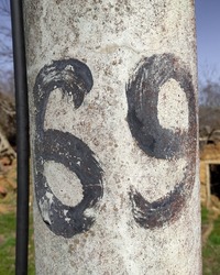Number sixty-nine in black on a concrete utility pole 