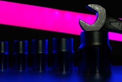 Spanner for 16mm is standing on a top of hexagon head. Dark purple tube is giving backlight for whole composition. Background picture.