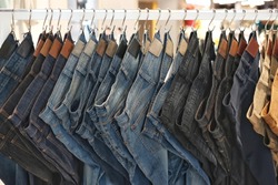 Many jeans hanging on a rack. Row of pants denim jeans hanging in closet. concept of buy , sell , shopping and jeans fashion .