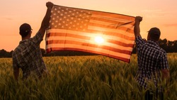 Two men energetically raised the US flag in a picturesque field of wheat