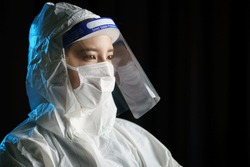 Woman wearing gloves, biohazard protective suit, face shield and mask. For corona virus or Covid-19 protection.