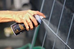 Man painting a fence with spray paint or aerosol paint 