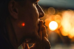 Close-up portrait of a man smoking at sunset with golden bokeh in the background