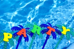 Party on the blue background of the pool. Festive decoration of a palm tree on a background of blue water.