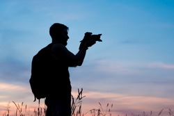 Silhouette of a young who like to travel and photographer, taking pictures of the beautiful moments during the sunset ,sunrise.