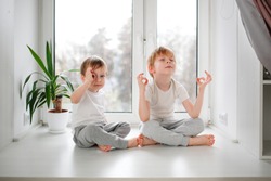 Children boys in pajamas on the windowsill, zen and meditation, calm