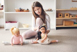 A child girl plays with dolls, a girl in a dance costume is engaged in gymnastics and ballet with a doll, role-playing and story games, sports and stretching, gentle colors