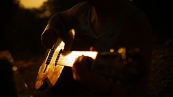 Man playing acoustic guitar at sunset