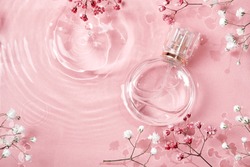 Glass perfume bottle in rose water background. Floral arrangement, splash of water