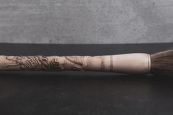 Chinese hand carved bone paintbrush on grey and black background.