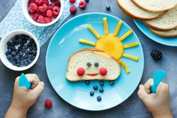 Creative idea for kid breakfast - sweet bread bun cloud with berry rain and fruit sun