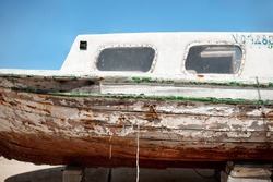 Old rotten wooden boat and bad old boards in need of restoration, reparation concept. Isolated on blue sky and sunny day