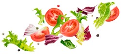 Falling salad of leaves with rucola, lettuce, radicchio, romano green frize and tomatoes isolated on white background