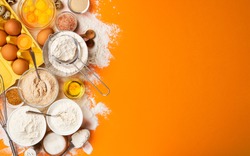 Baking ingredients for dough on yellow color background, top view of flour, eggs, butter, sugar and kitchen utensils for homemade baking. Cooking concept banner with copy space for text