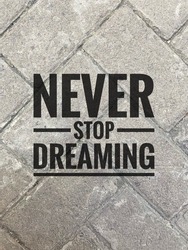 Inspirational Motivation Quotes. Never Stop Dreaming in gray bricks background