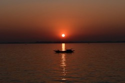 Setting sun makes a graceful view with dingy boat on Meghna river