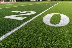 Synthetic turf football field twenty, 20, yard line in white. 