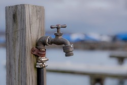 Outside water spigot, hose bib, on a wooden post.
