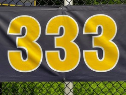 333 foot ft baseball field distance sign in yellow and black mounted on the black vinyl outfield fence.
