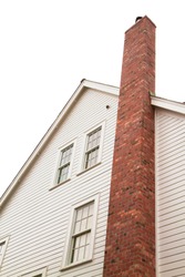 Side of older style white house with tall red brick chimney