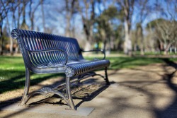 Narrow DOF HDR image of a black metal park bench diminishing to a very soft background