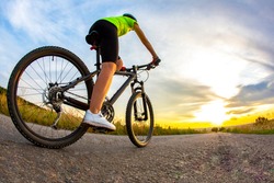 Beautiful sporty cyclist rides a bicycle on the road against the backdrop of beautiful nature and sunset. hobbies and sports