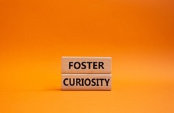 Foster curiosity symbol. Concept word Foster curiosity on wooden blocks. Beautiful orange background. Business and Foster curiosity concept. Copy space