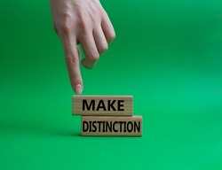 Make distinction symbol. Concept words make distinction on wooden blocks. Beautiful green background. Businessman hand. Business and make distinction concept. Copy space.. Conceptual image