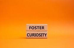 Foster curiosity symbol. Concept word Foster curiosity on wooden blocks. Beautiful orange background. Business and Foster curiosity concept. Copy space. Conceptual image