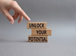 Unlock your Potential symbol. Wooden blocks with words Unlock your Potential. Beautiful grey background. Businessman hand. Business and Unlock your Potential concept. Copy space.