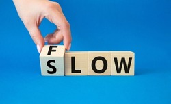 Flow and Slow symbol. Concept words Flow and Slow on wooden cubes. Beautiful blue background. Businessman hand. Business and Flow and Slow concept. Copy space.