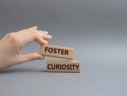 Foster curiosity symbol. Concept word Foster curiosity on wooden blocks. Beautiful grey background. Businessman hand. Business and Foster curiosity concept. Copy space