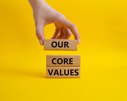 Our core values symbol. Concept words 'Our core values' on wooden blocks. Beautiful yellow background. Businessman hand. Business and Our core values concept. Copy space.