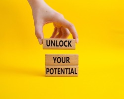 Unlock your Potential symbol. Wooden blocks with words Unlock your Potential. Beautiful yellow background. Businessman hand. Business and Unlock your Potential concept. Copy space.