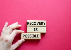 Recovery is possible symbol. Concept words Recovery is possible on wooden blocks. Beautiful red background. Businessman hand. Business and Recovery is possible concept. Copy space.