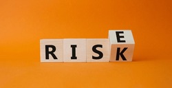 Rise vs Risk symbol. Turned wooden cubes with words Risk vs Rise. Beautiful orange background. Businessman hand. Business and Rise vs Risk concept. Copy space