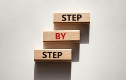 Step by step symbol. Wooden blocks with words Step by step. Beautiful white background. Business concept. Copy space.