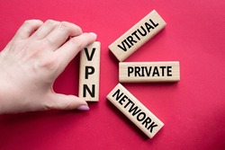 VPN - Virtual Private Network. Wooden cubes with word VPN. Businessman hand. Beautiful red background. Business and VPN concept. Copy space.