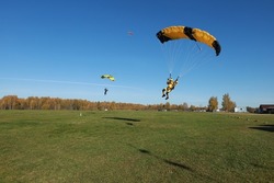 Skydiving. Skydivers are landing on the field.