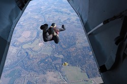 Skydiving.  A skydiver is jumping out of a plane.