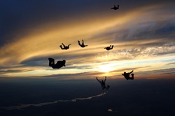 The group of skydivers in the sunset sky.