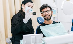 Dentist with patient showing him a periapical x-ray, View of dentist with patient reviewing dental x-ray. Dentist showing periapical x-ray to patient