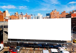 Big blank billboard in New York City, surrounded by highrise buildings and a bright blue sky overhead