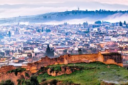 Fez, Morocco aerial view on a frosty foggy winter morning. The ancient city wall is in the foreground and behind it, an overview of the old neighborhood.