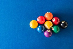 diamond shape of 9-ball pool balls placed in rack position on blue felt table, top view, copy space