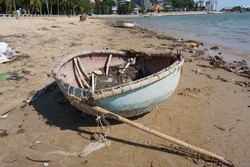 Damaged fishing basket boat abandoned on the beach
