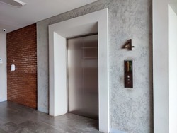 Modern steel elevator cabins in a business lobby or Hotel, Store, interior, office, perspective wide angle with classic brick wall beside it. No people