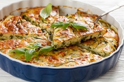Scarpaccia salata, tuscan zucchini savory tart cut in slices in a baking dish on a white wooden table table, italian cuisine, close-up