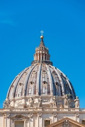 The detailed view of dome summit of Papal Basilica of St. Peter in the Vatican against blue sky and copy space. Rome, Italy